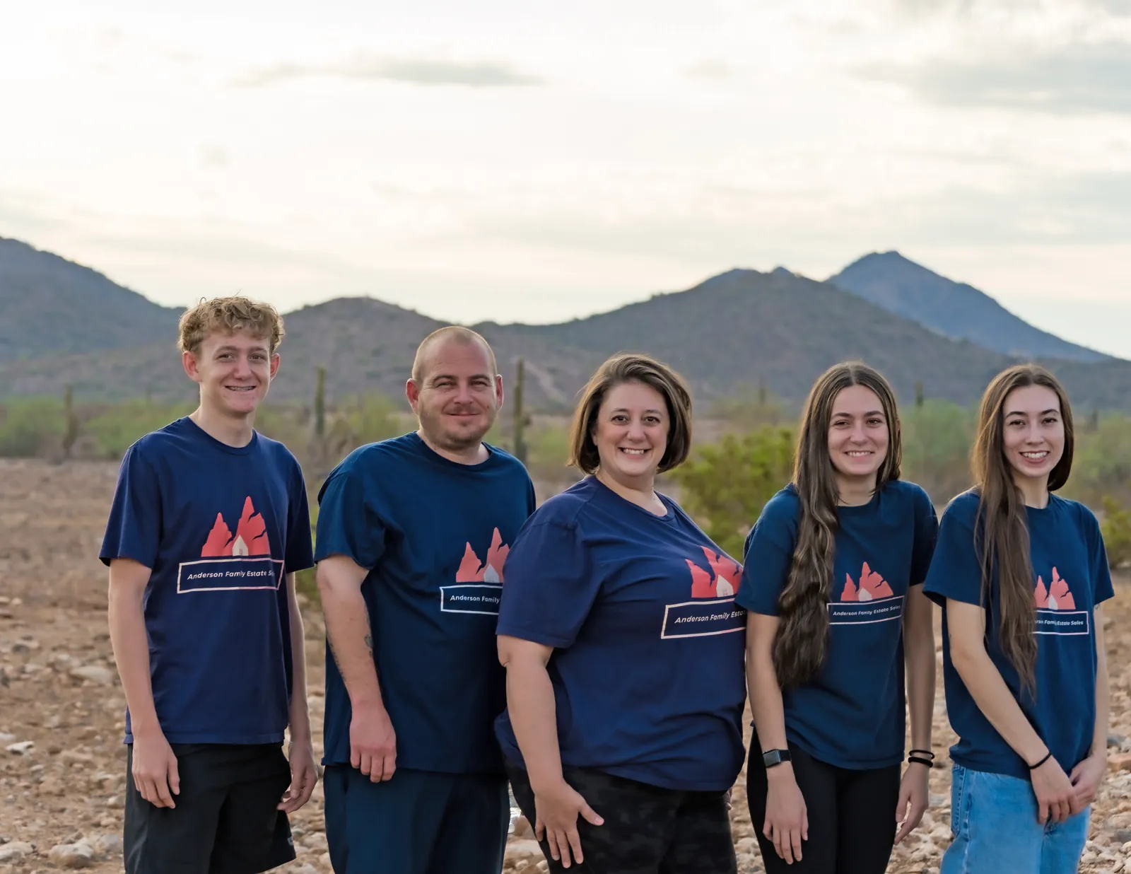 The Anderson family, five of them in matching navy company T-shirts, standing in the Arizona desert with mountains behind them
