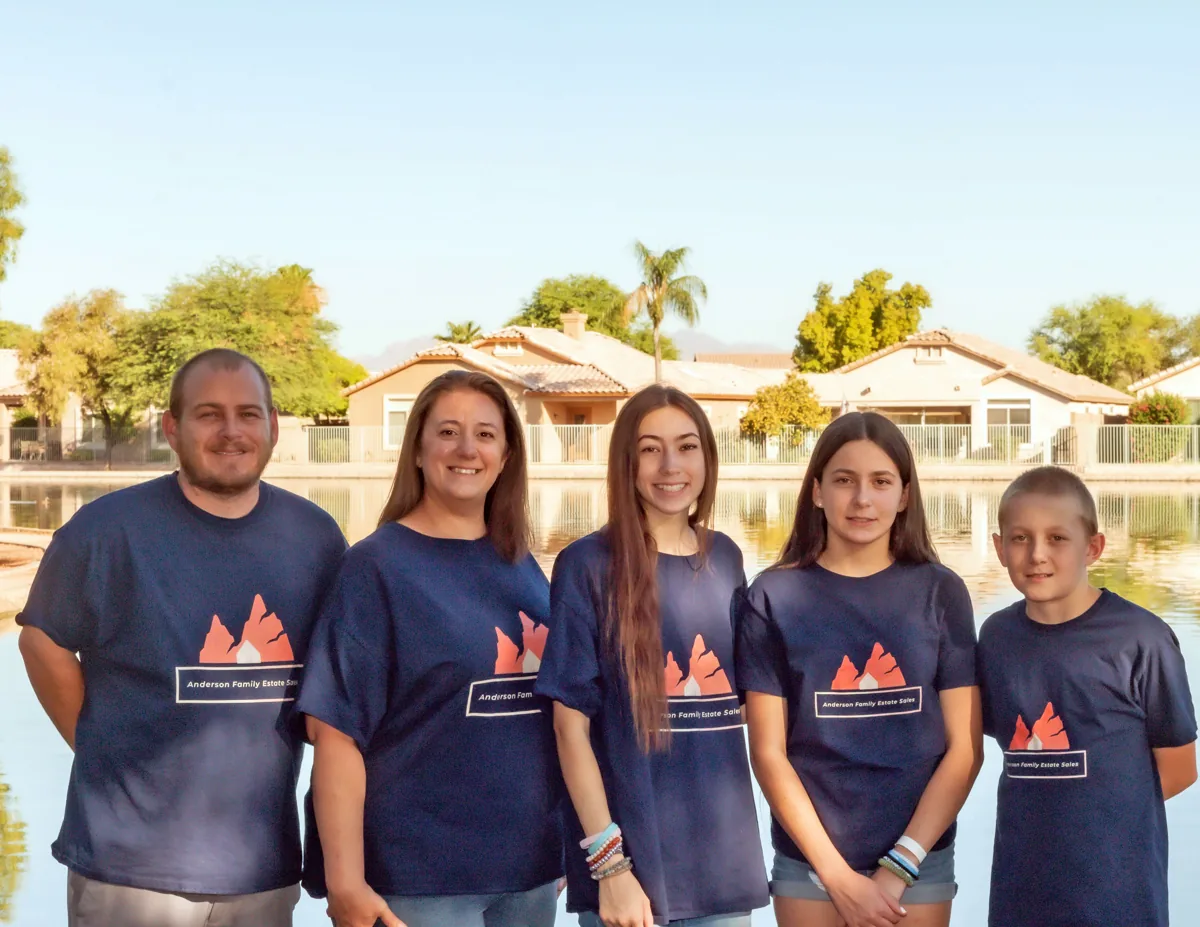 The Anderson family, five of them in matching navy company T-shirts, standing by a lake
