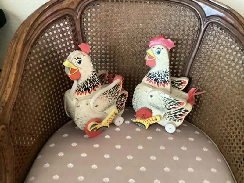 Pair of hen figurines on a cane chair