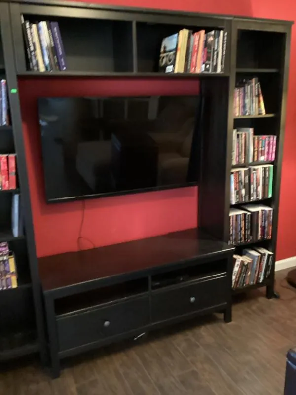 Black entertainment wall unit with bookshelves and a TV