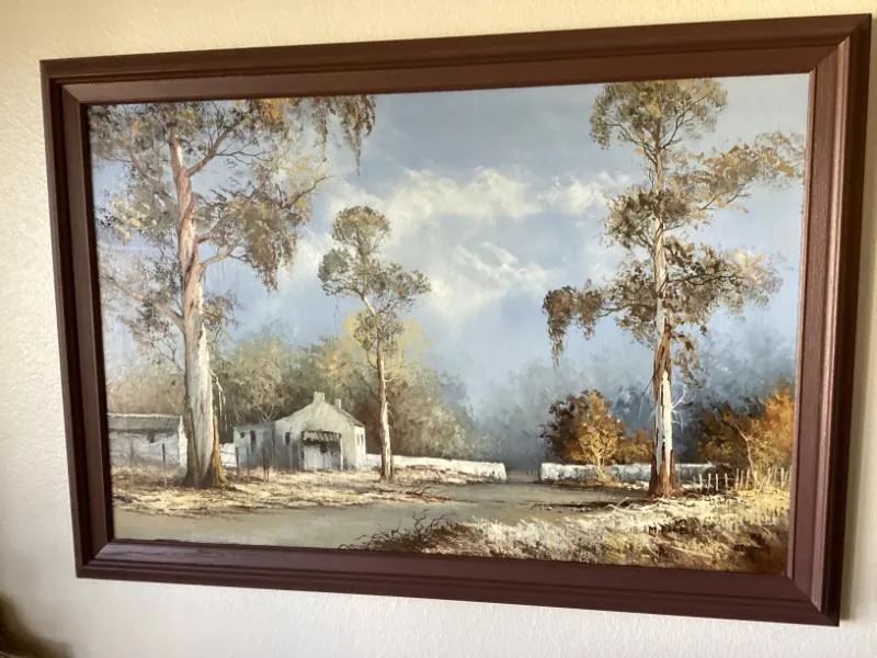 Framed landscape painting of trees and a house