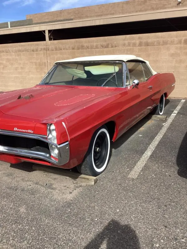 Red Pontiac with a white top in a parking lot