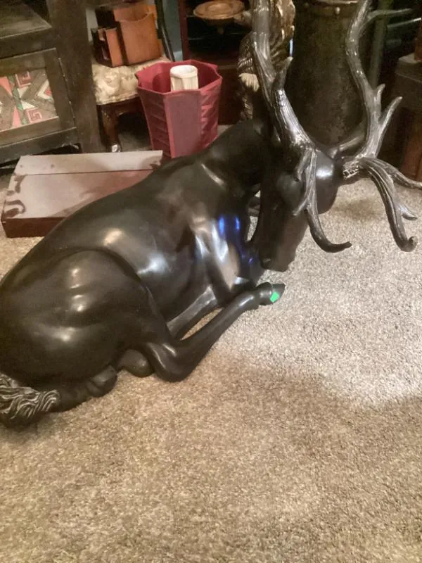 Large dark deer statue lying on the carpet