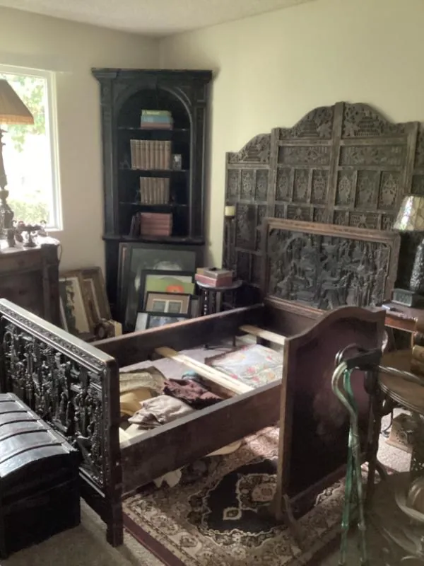 Carved wood bed frame beside a corner bookshelf