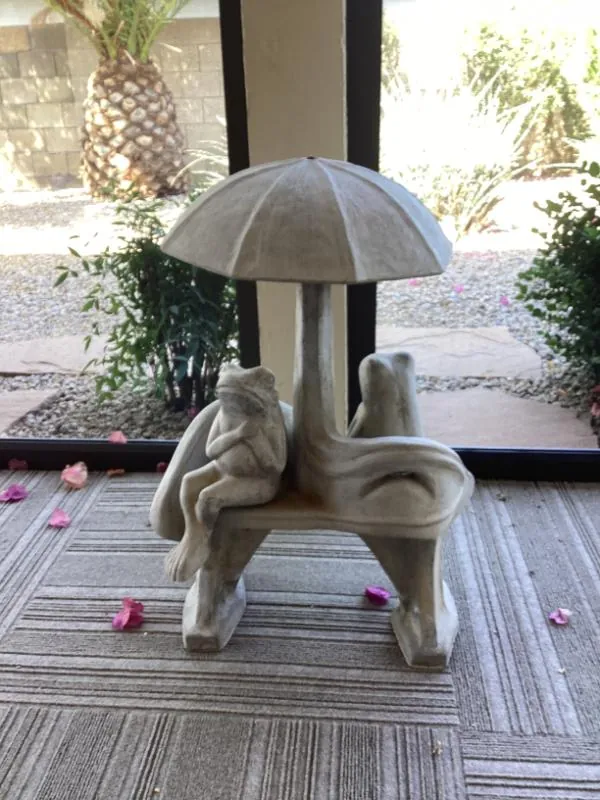 Stone garden statue of children sitting under an umbrella