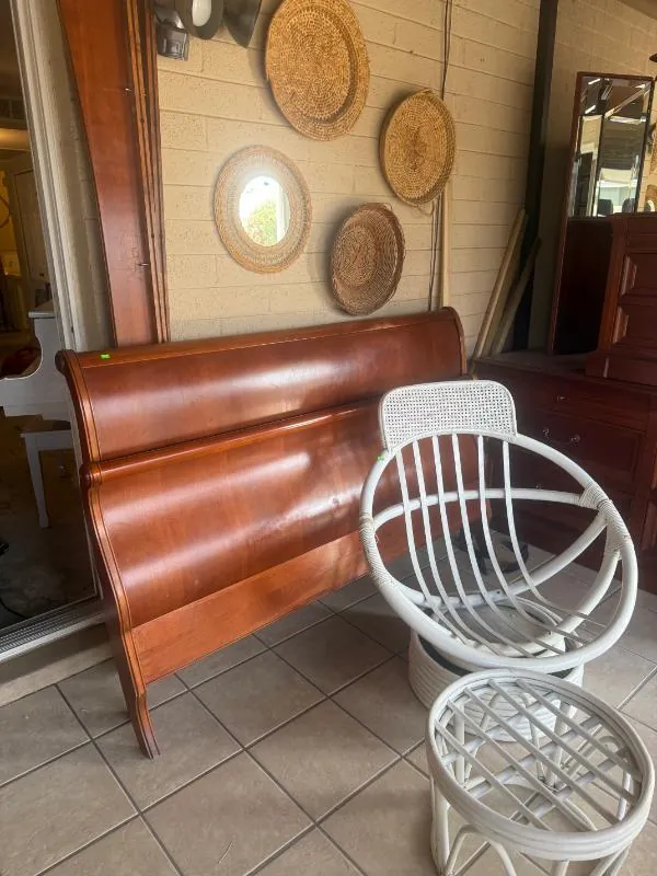 Wood sleigh bed beside white wire chairs