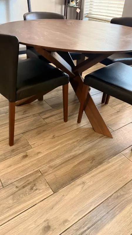 Round wood dining table with dark chairs