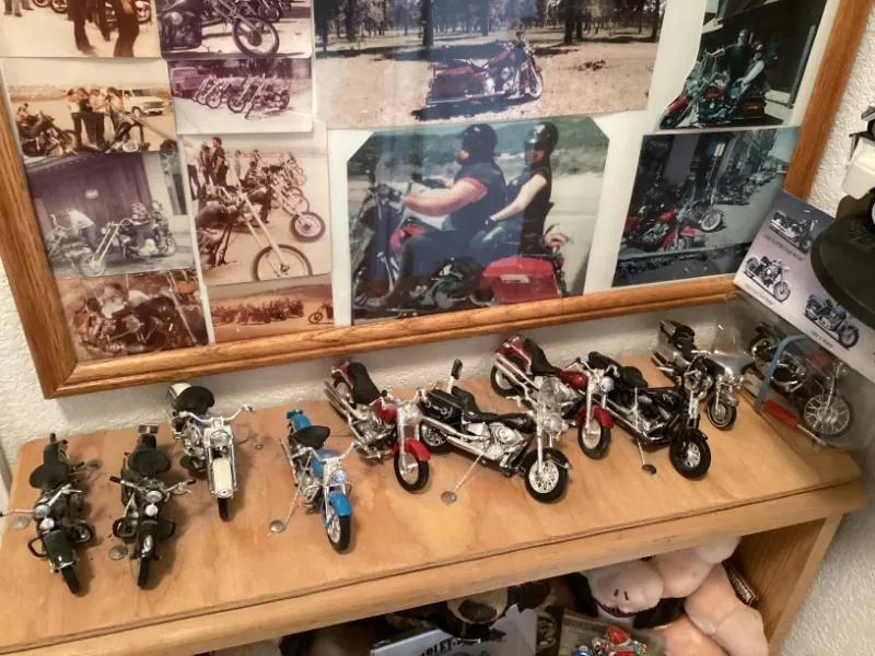 Shelf of model motorcycles below framed photos
