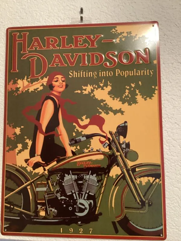 Harley-Davidson metal sign with a woman on a motorcycle