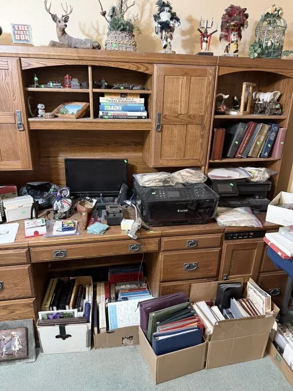 Wood desk with a hutch, stacked with books and office items