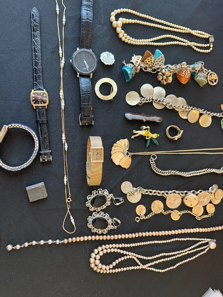 Watches, necklaces and jewelry laid out on a dark cloth