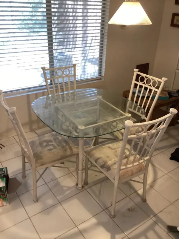 Glass-top dining table with white metal chairs