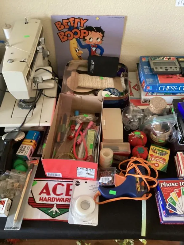 Board games and craft supplies on a table, with a Betty Boop sign