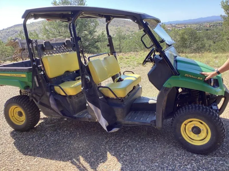 Green and yellow side-by-side utility vehicle parked on gravel