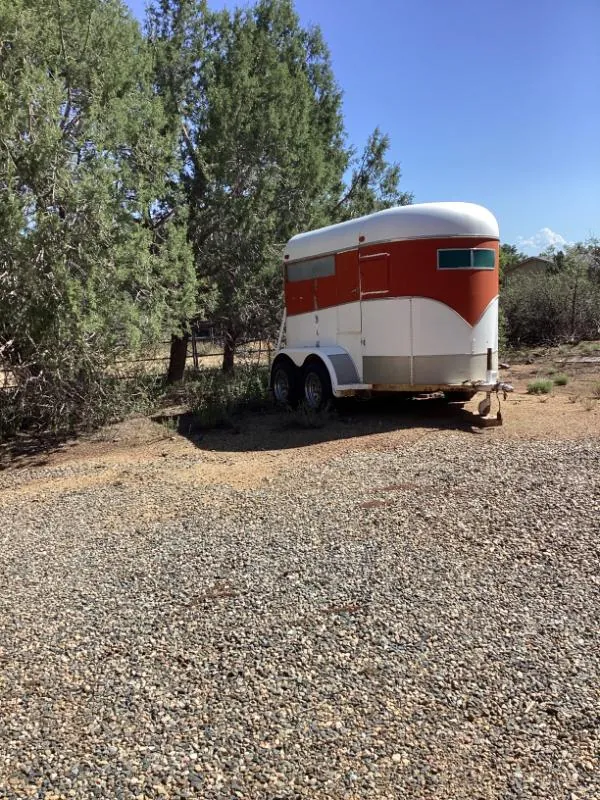 Red and white two-axle trailer parked among trees