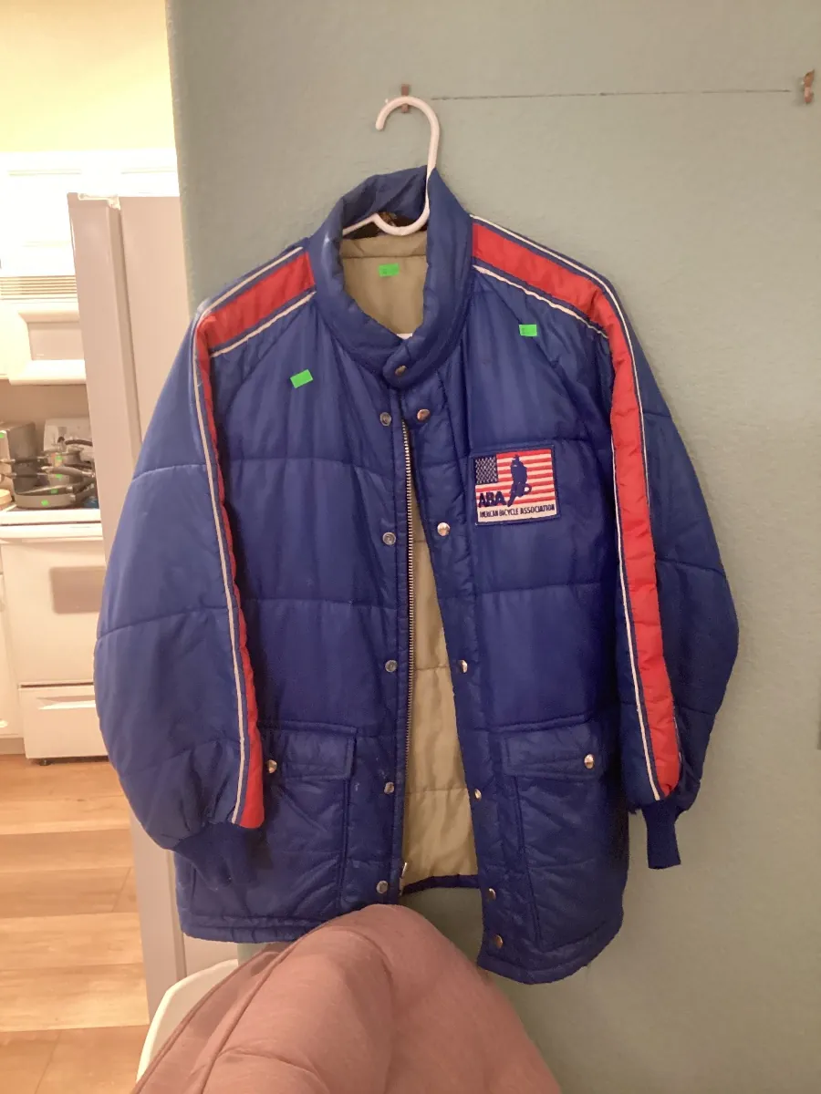 Blue quilted jacket with red stripes on a hanger