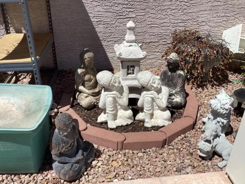Garden statues and a stone pagoda lantern in a gravel yard