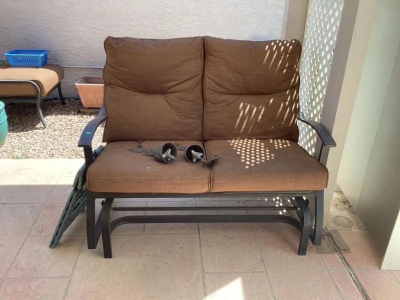 Outdoor glider loveseat with brown cushions