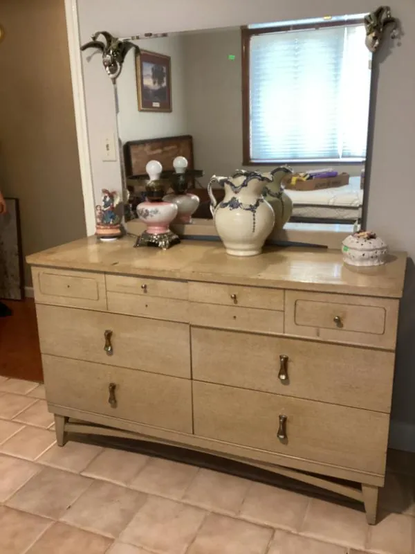 Light wood-tone dresser with a mirror, topped with lamps and a porcelain pitcher