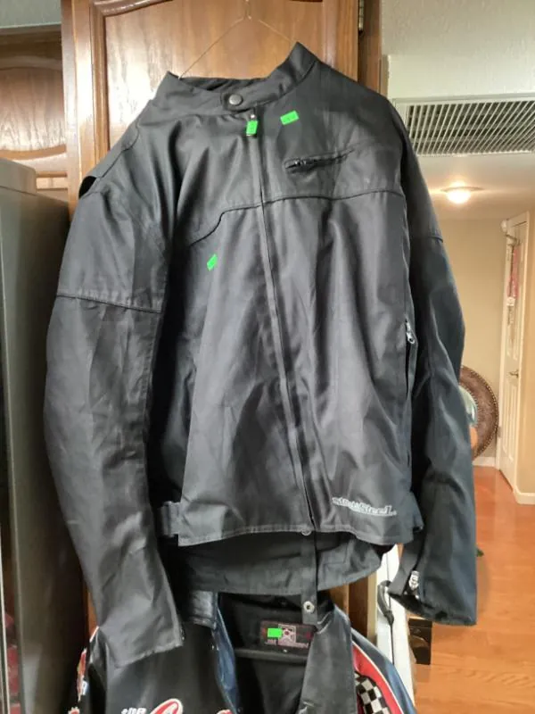 Black mesh jacket with a Street & Steel logo, hanging on a door