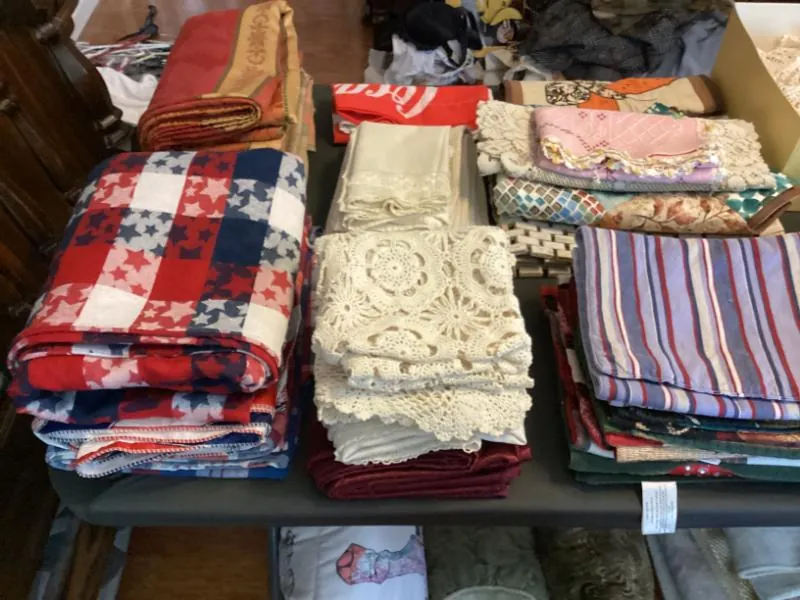 Tables of folded blankets, crocheted throws and linens