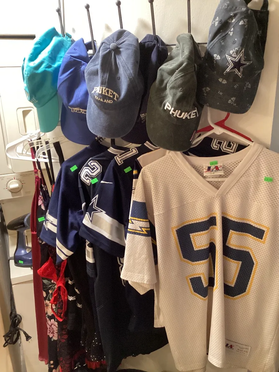 Baseball caps and sports jerseys hanging in a closet