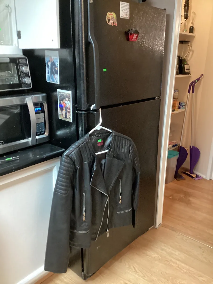 Black leather jacket hanging on a refrigerator door
