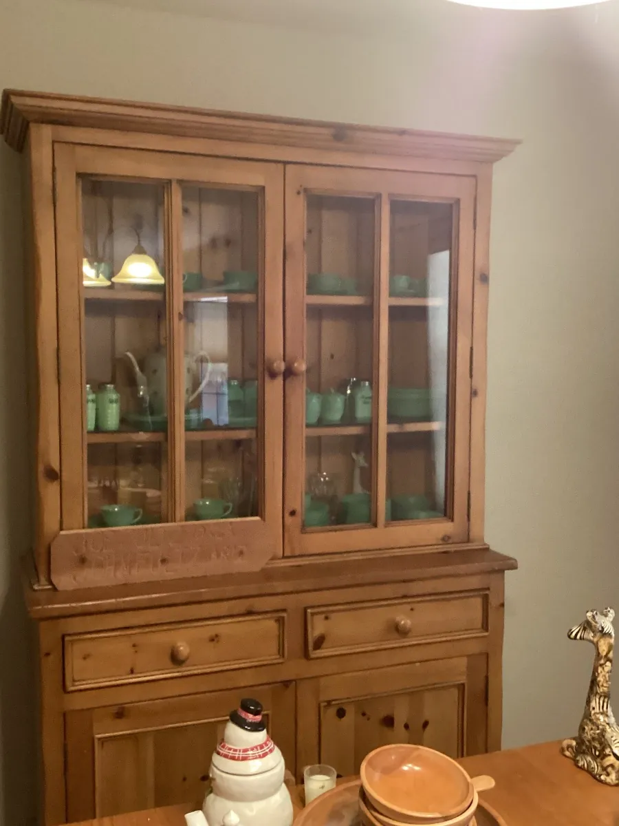 Wood china hutch with glass doors, filled with green glassware