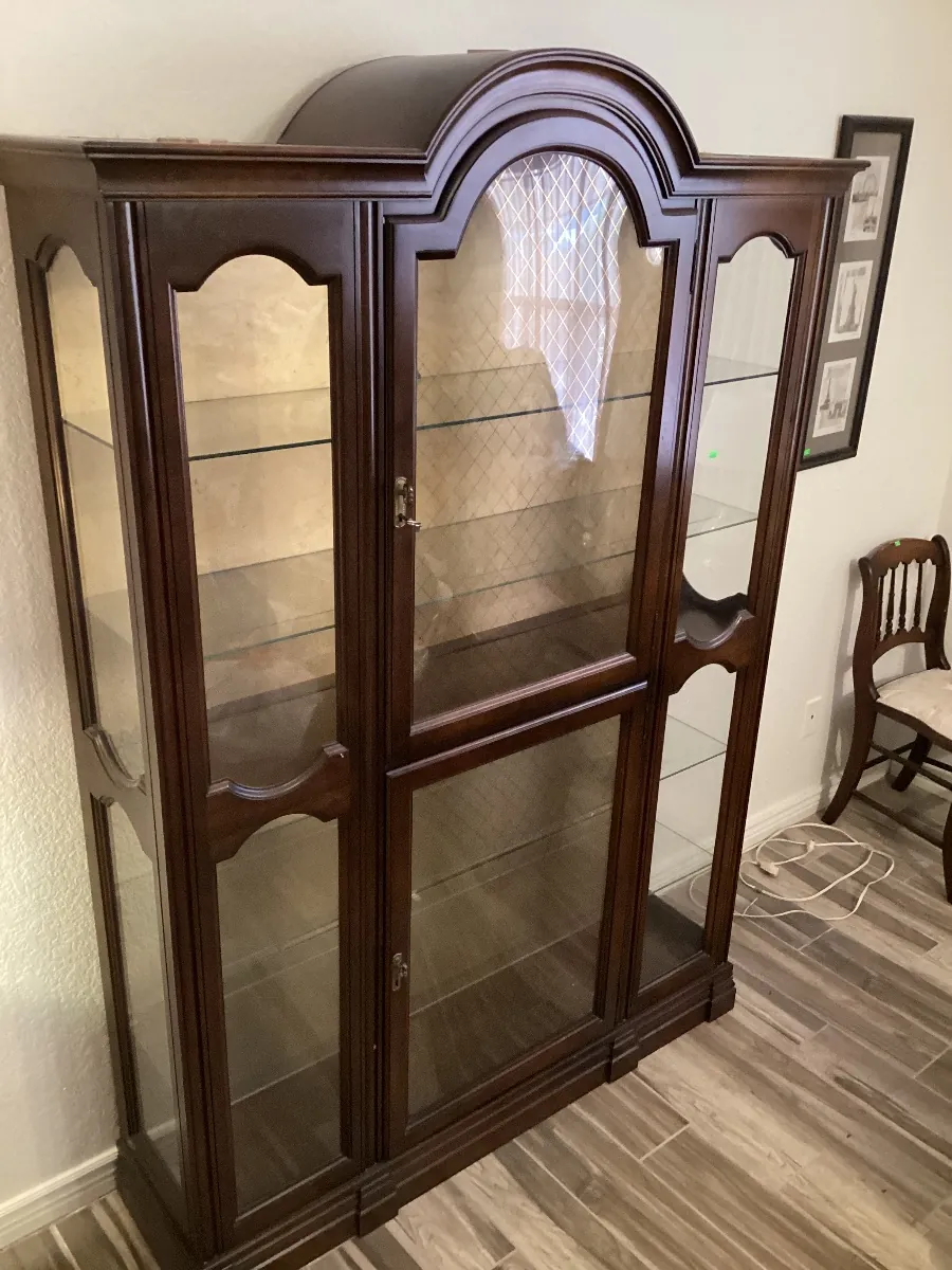 Dark wood curio cabinet with an arched top and glass doors