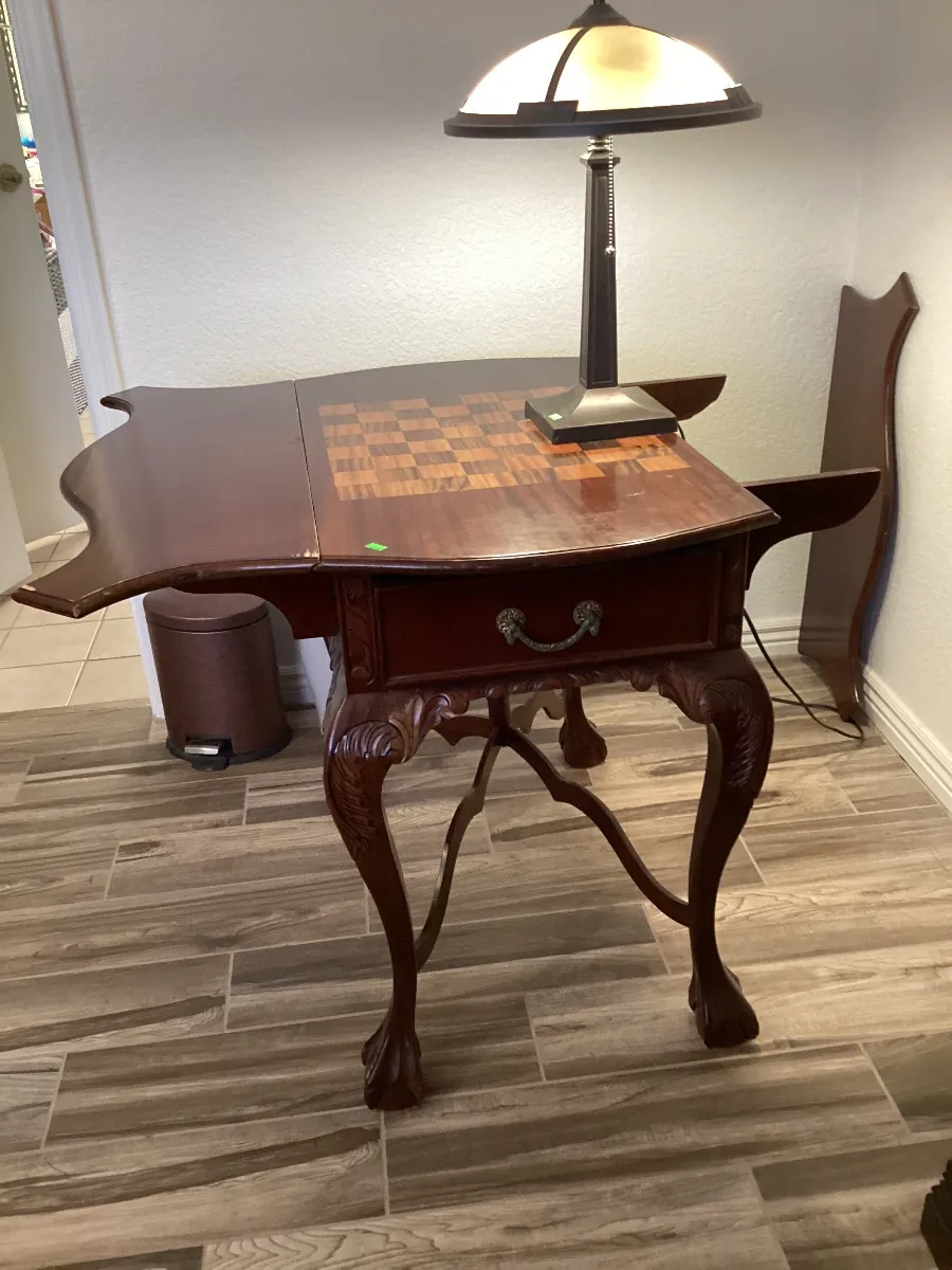 Wood drop-leaf table with a checkerboard inlay top and carved legs